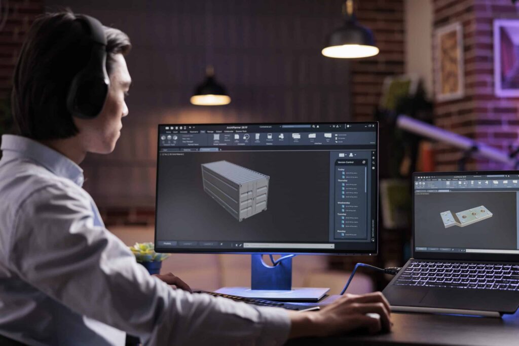 Designer working on a 3D CAD model on a monitor and laptop
